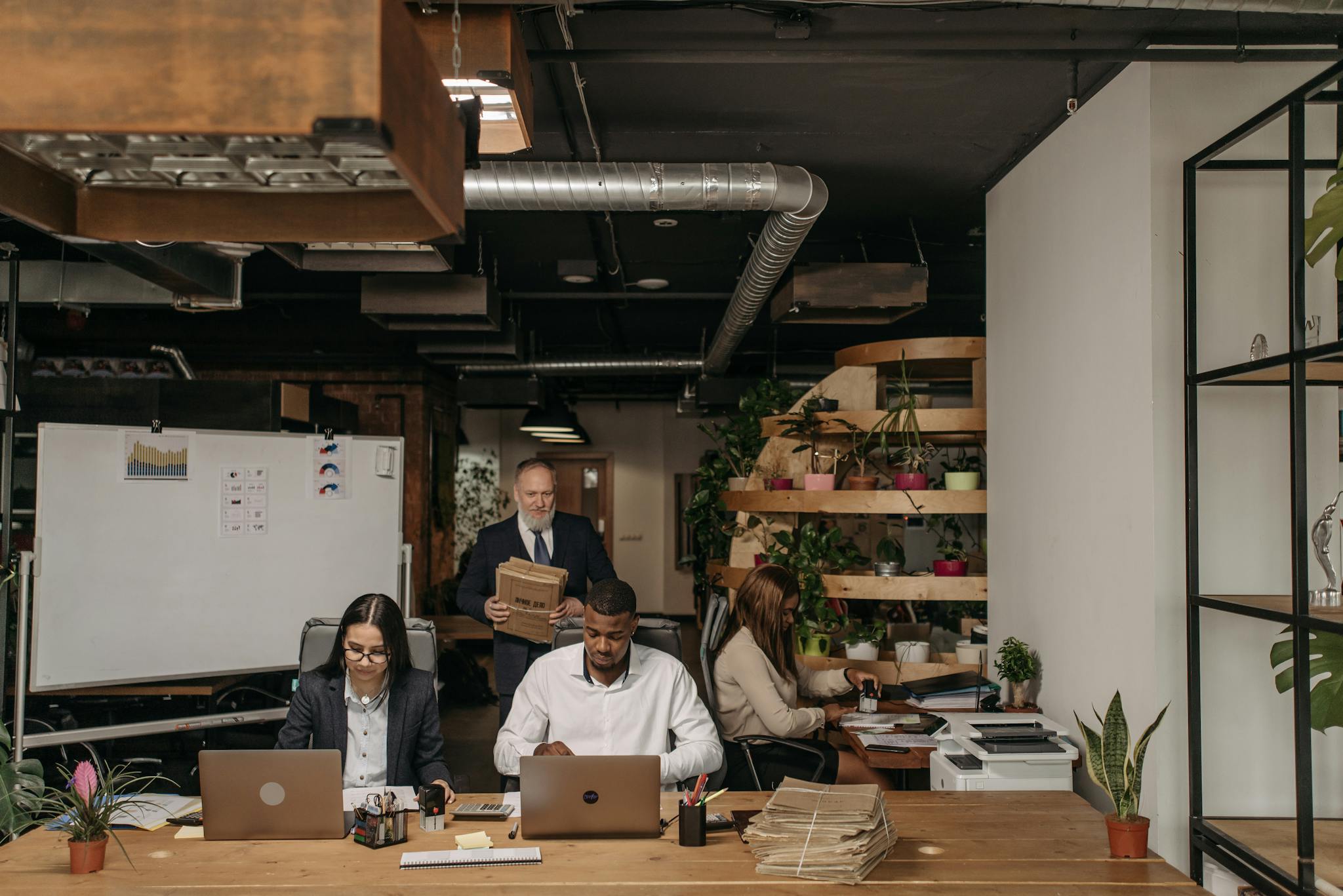 Diverse office team working on laptops and documents in an open-plan workspace.